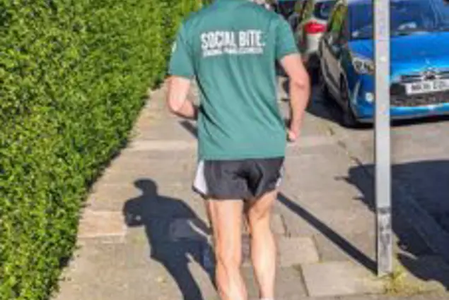 A man in a green tshirt runs away from the camera