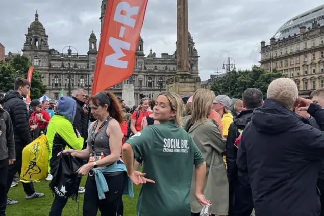 a young woman in a Social Bite tshirt looks over her shoulder before her 10k race begins